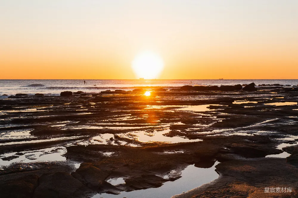 高清摄影 夕阳西下，海天相接处点缀着岩石。