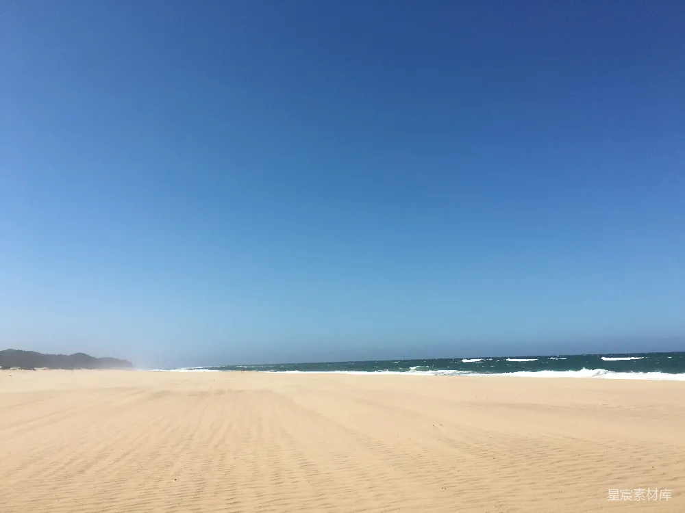 高清摄影 一片沙滩，海浪从海洋涌来。