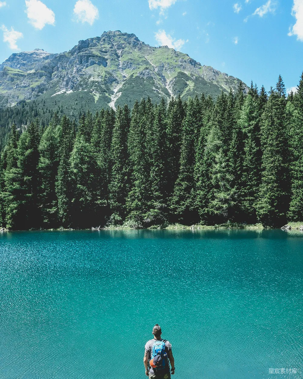 高清摄影  男子透过湖景望着，湖边有pine trees，在蓝天下。