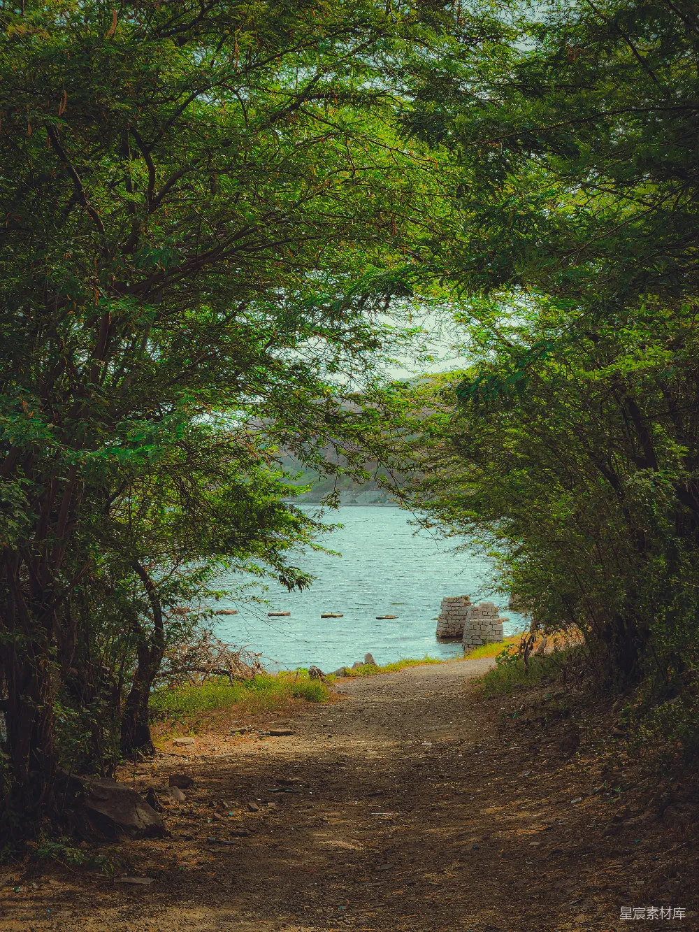 高清摄影 路边一条泥土小路上有一张长椅，旁边是一片水域。