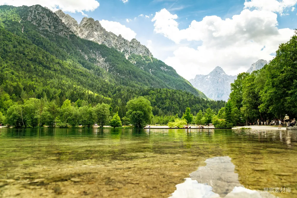 高清摄影 绿树环绕着湖与山，在蓝天白云下白天景色