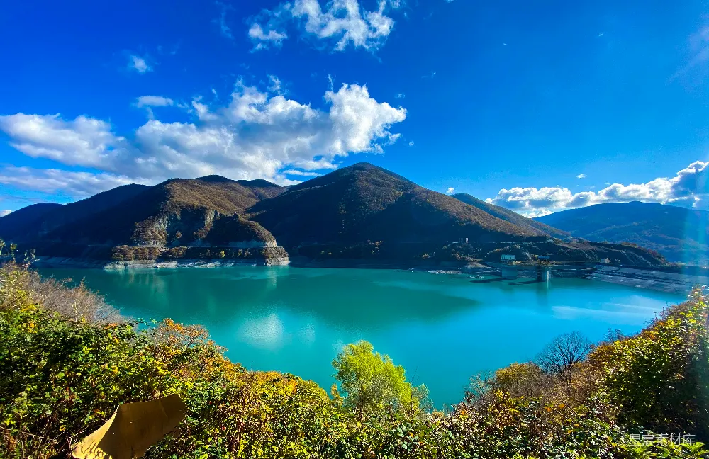 高清摄影 白天湖周围被绿树和群山环绕，在蓝天之下。