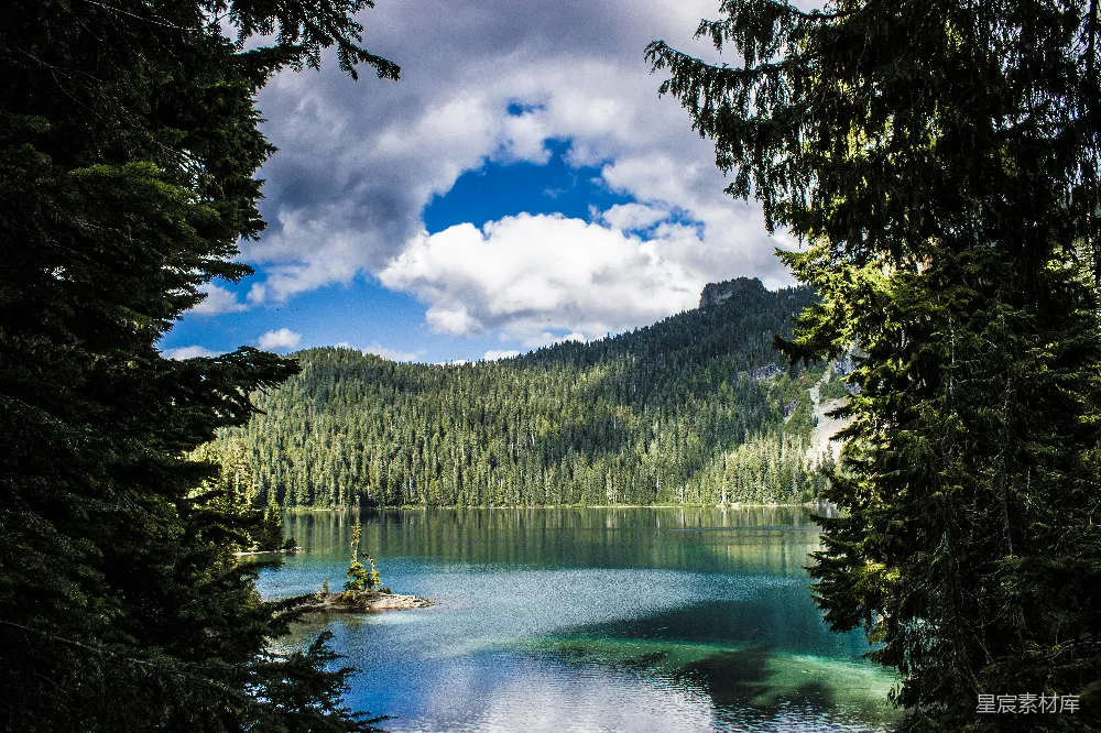 高清摄影  一个被树木环绕的湖泊，背景是山峦。