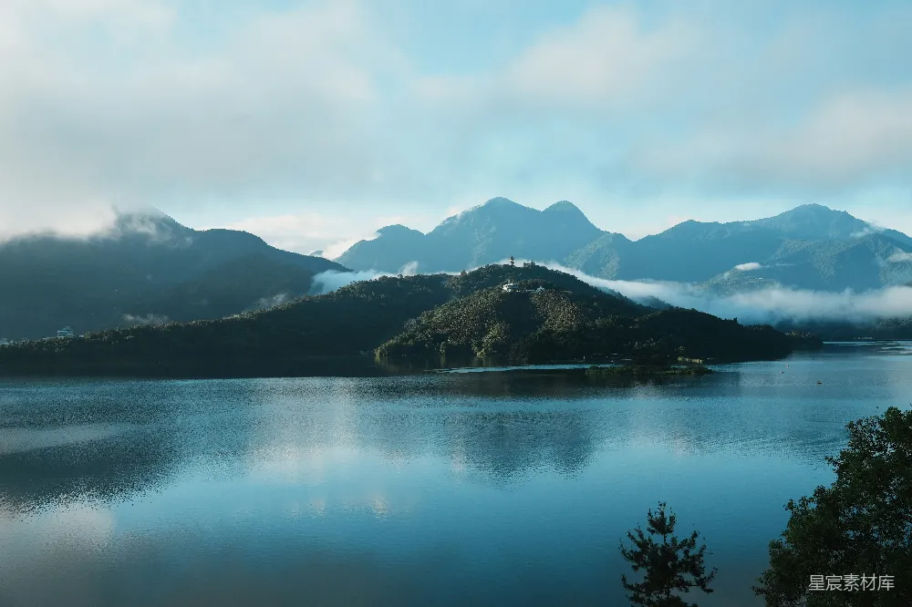 高清摄影 平静的湖泊映照着云雾缭绕的山峦，在一片阴天的背景下。