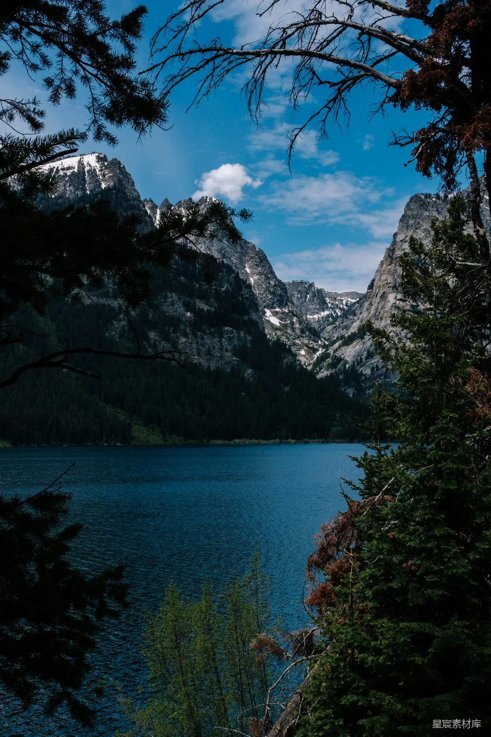 高清摄影 白天绿树环绕着湖和山，蓝天之下。