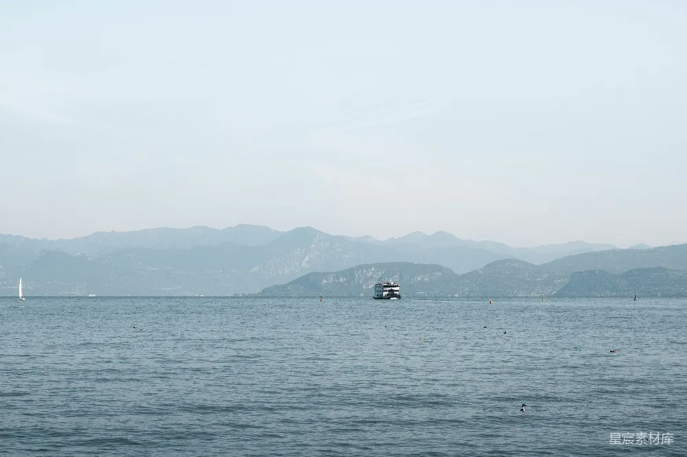 高清摄影 一艘船在平静的湖面上航行，远处有山峦。