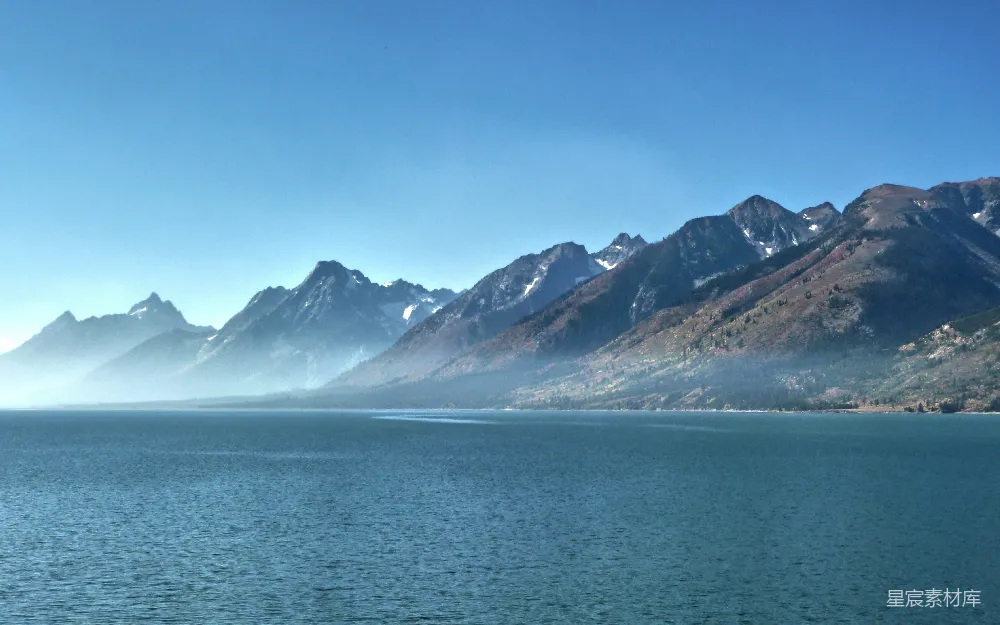 高清摄影 白天，蓝海上方覆盖着白雪的山峰，蓝天背景下。