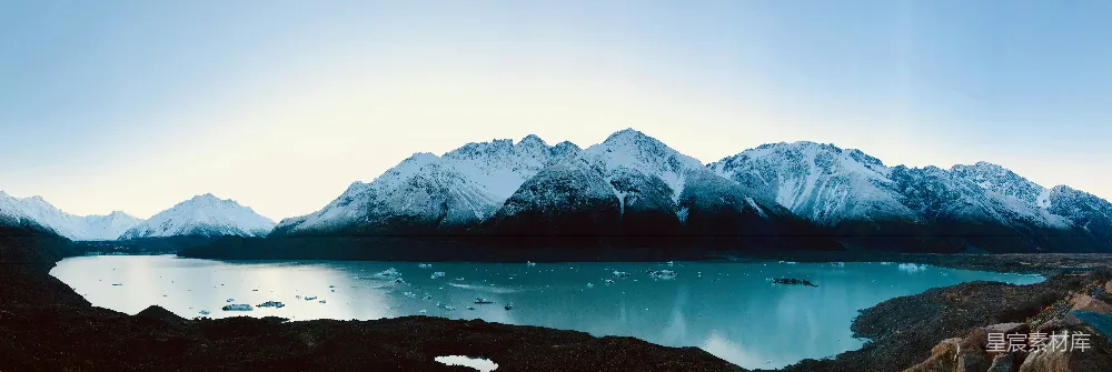高清摄影 白天山顶附近有一片积雪的山体靠近水域
