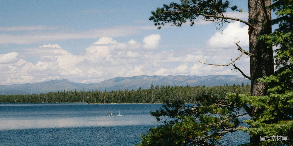 高清摄影 一片被树木环绕的湖泊，背景是群山。