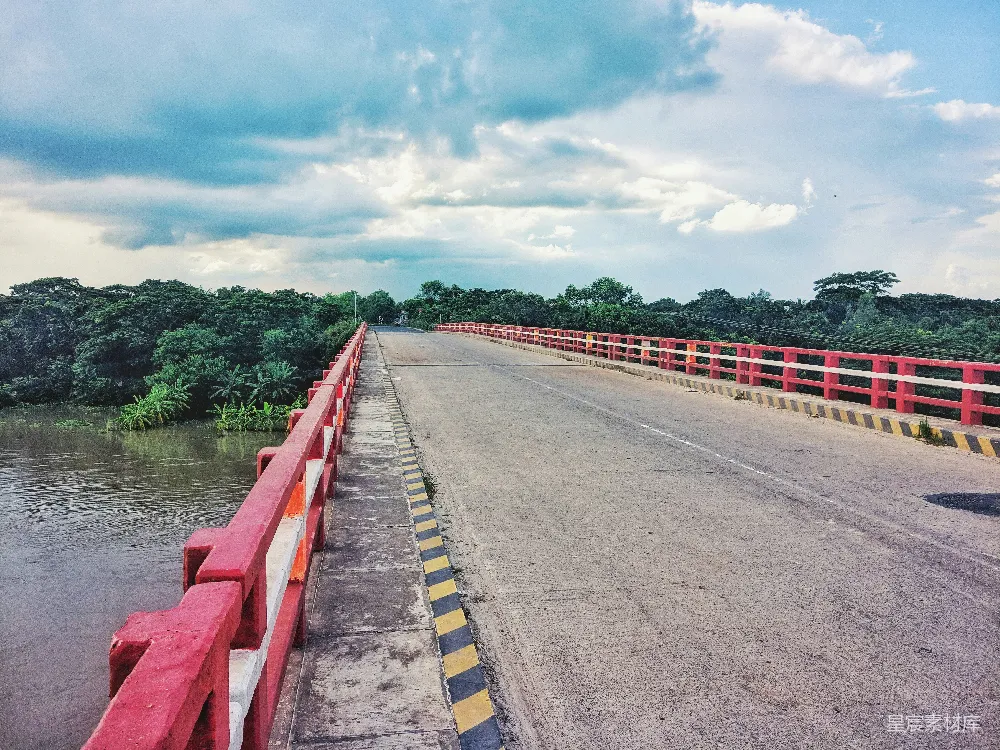 高清摄影 白天河边红色和白色道路两侧白云下