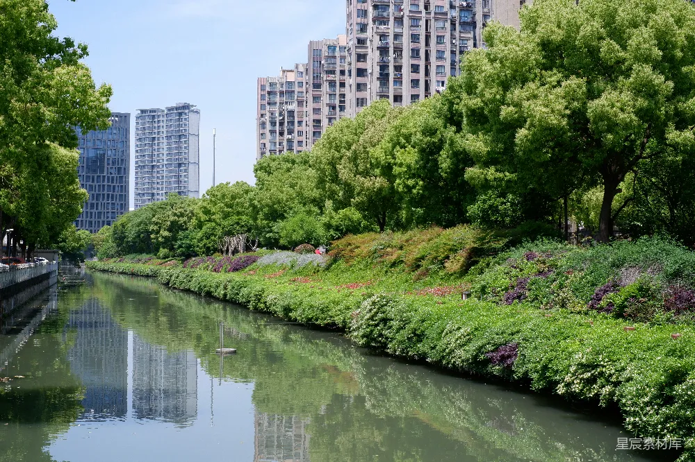 高清摄影 一条运河流过绿树与现代建筑之间。