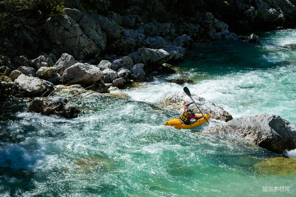 高清摄影 一个人在一条岩石嶙峋、碧蓝的河流中划独木舟。
