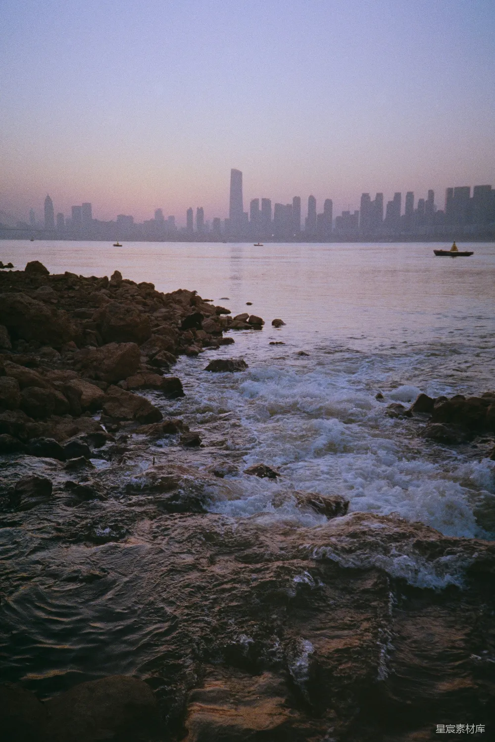 高清摄影 黄昏时分的城市天际线与岩石海岸相对。