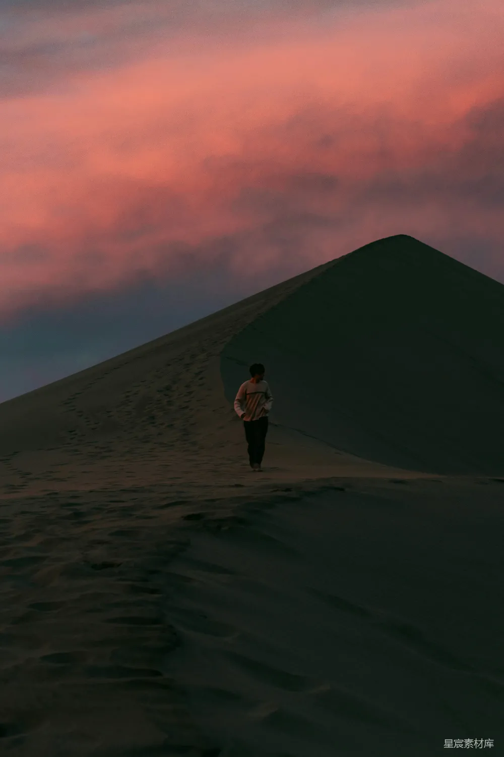 高清摄影 夕阳下男子在沙丘上行走。