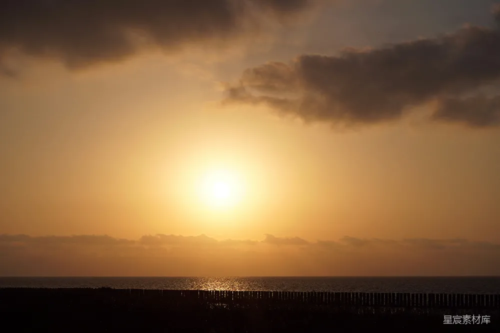 高清摄影 在阴天的一天，太阳正沉落在海面上。