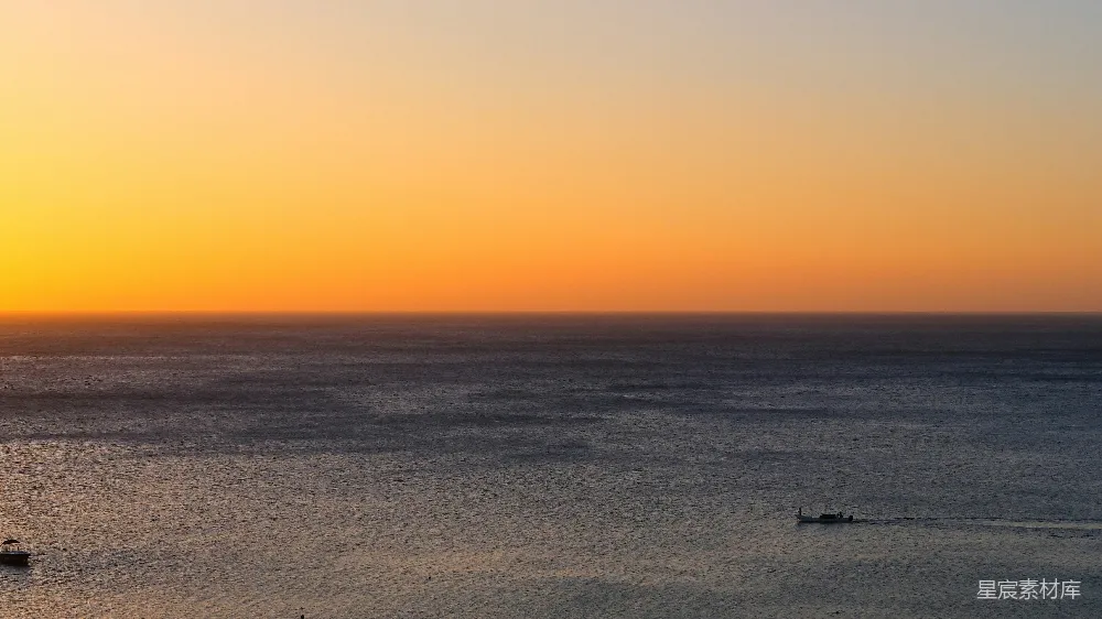 高清摄影 夕阳下的平静海洋与远处的船只