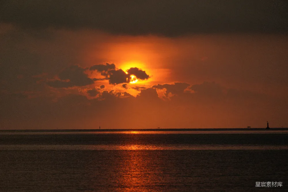高清摄影 夕阳映照在海洋之上，云彩缭绕。