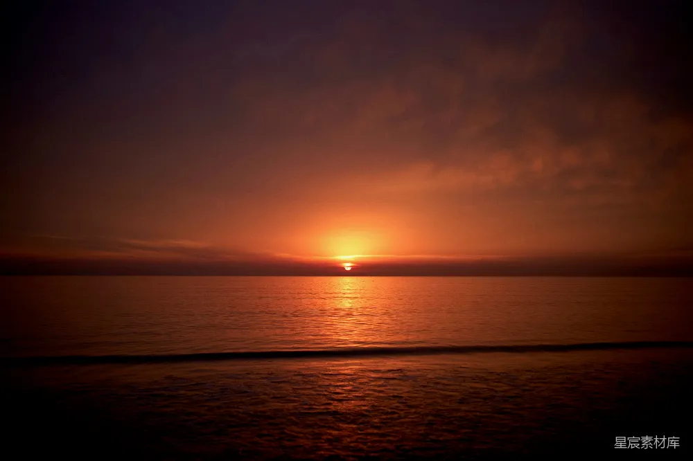 高清摄影 在阴云密布的一天里，夕阳正沉落在海面上。