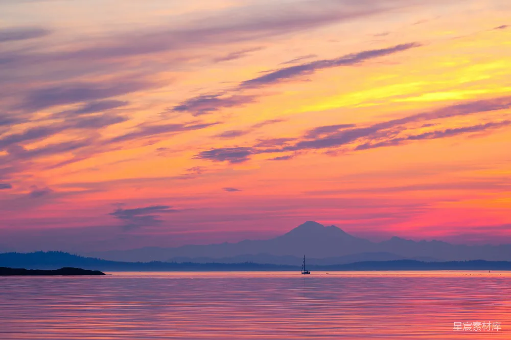高清摄影 夕阳下水中的一叶小舟，背景是山峦。