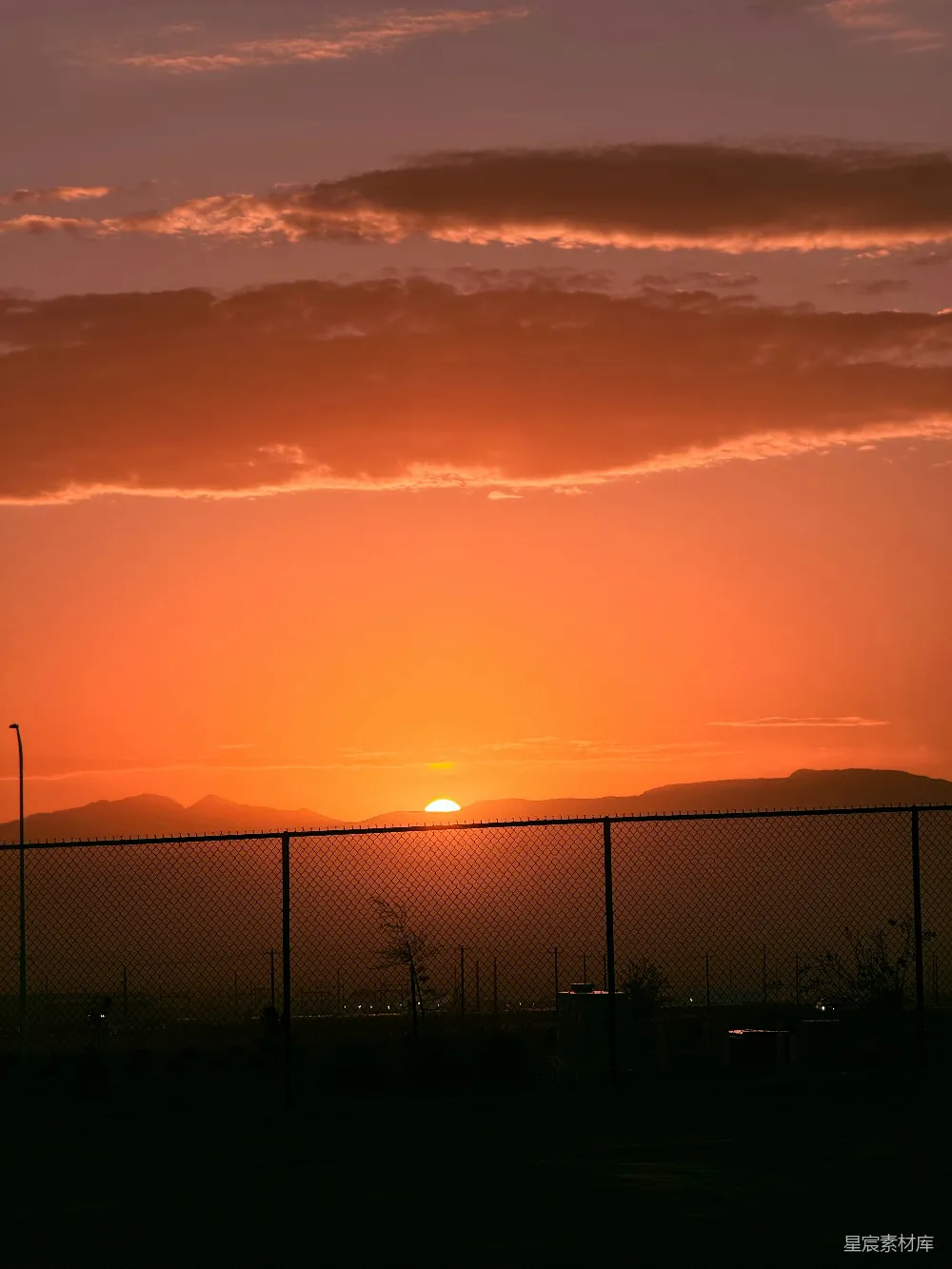 高清摄影 夕阳落在一道铁丝网围栏后面