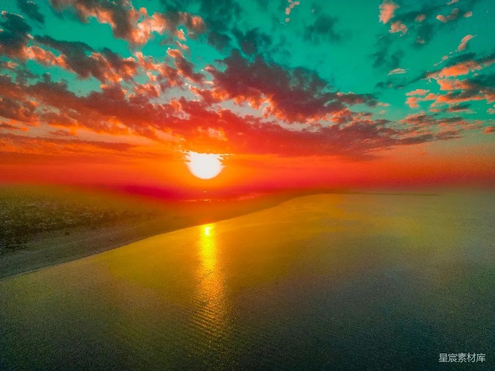 高清摄影 一片绚烂的夕阳映照在平静的大海上，天空中有色彩斑斓的云朵。