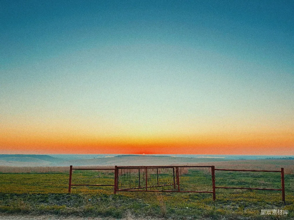 高清摄影  草地上一座红色的门楼，背景是夕阳。