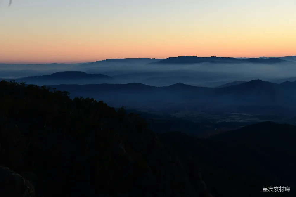 高清摄影 山脚下一只鸟飞过，背景是夕阳西下。