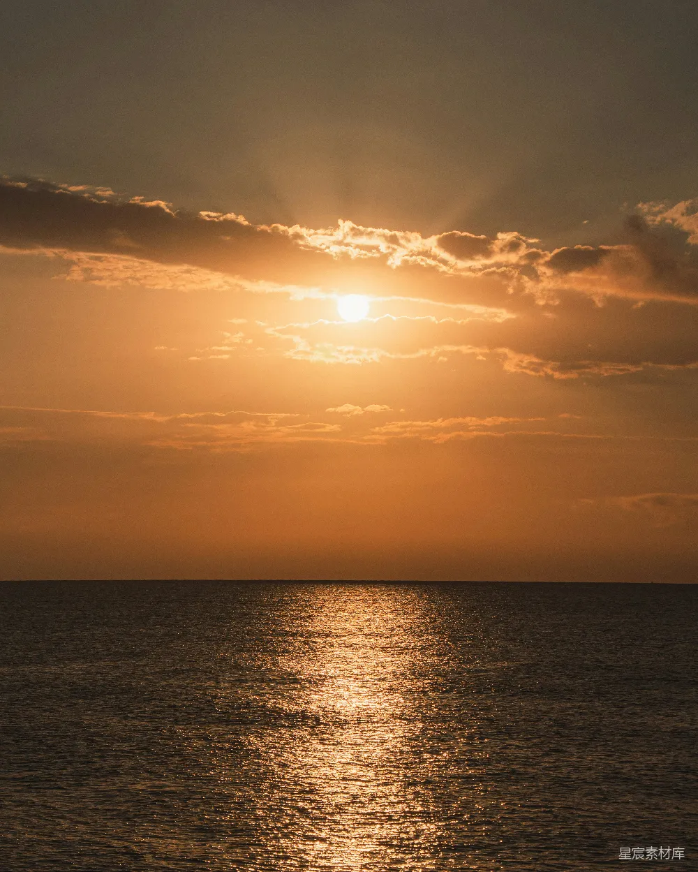 高清摄影 金色的夕阳照耀在大海之上，阳光透过云层洒落。