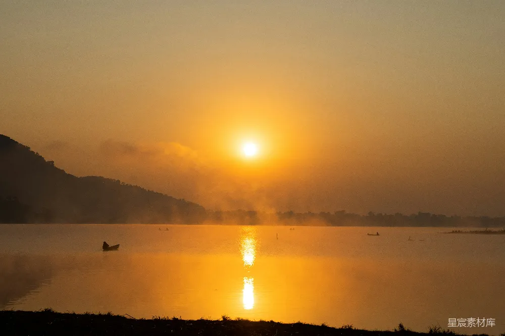 高清摄影 湖面上夕阳西下，一艘小船在水中。