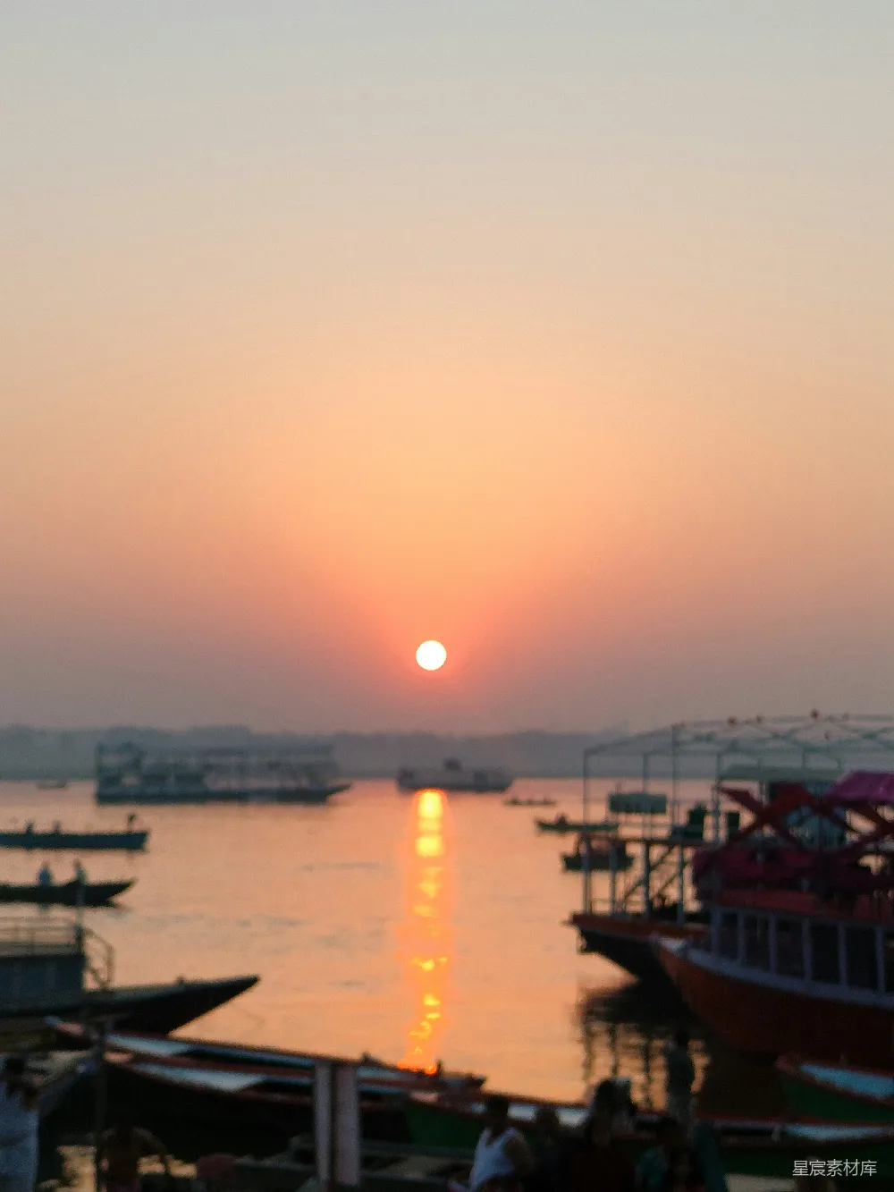高清摄影 橙色的夕阳映照在一条河上，河上有船只。