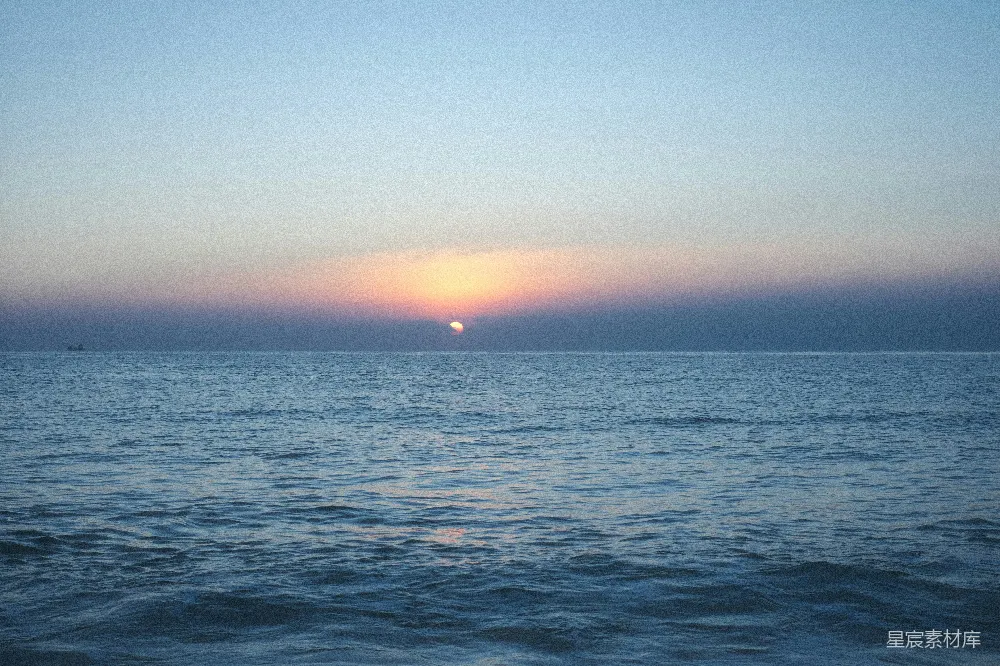 高清摄影 夕阳西下，海面上有一艘船在远处。