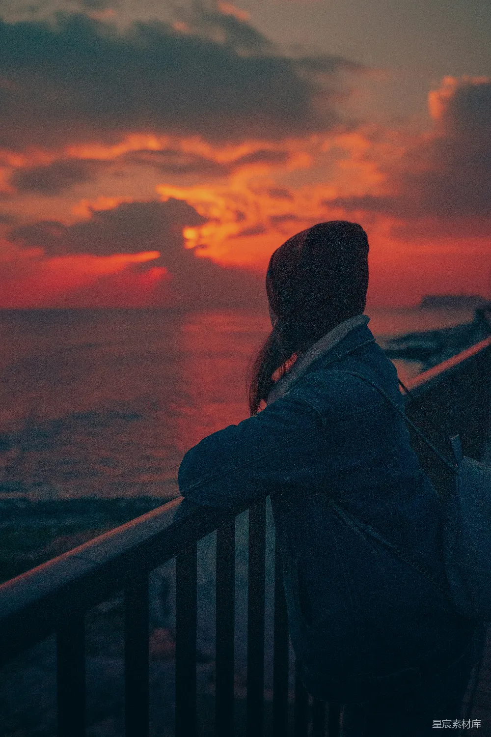 高清摄影 黑色夹克的男人站在夕阳下近 railing 处站立。