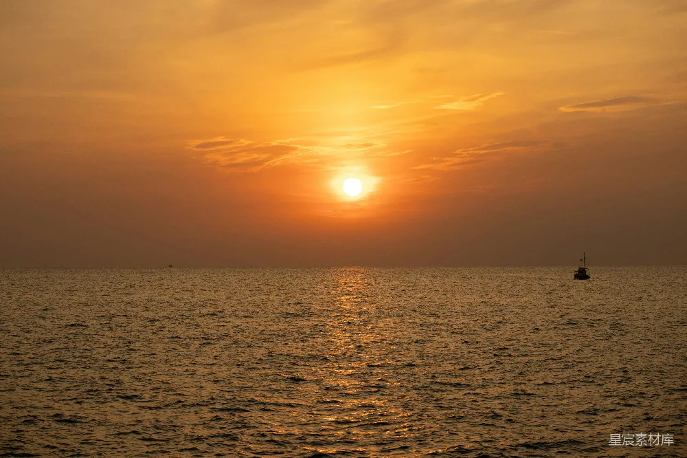 高清摄影 夕阳西下，海天相接处有一艘小船。