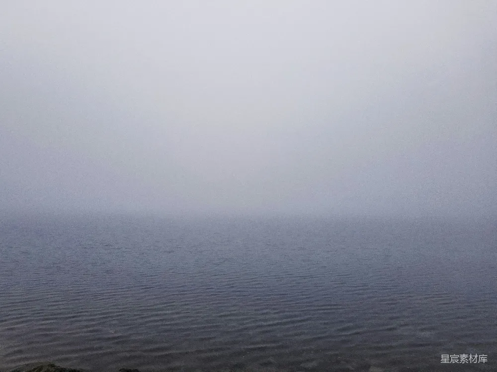 高清摄影 一片广阔的水域坐落在阴云密布的天空下。
