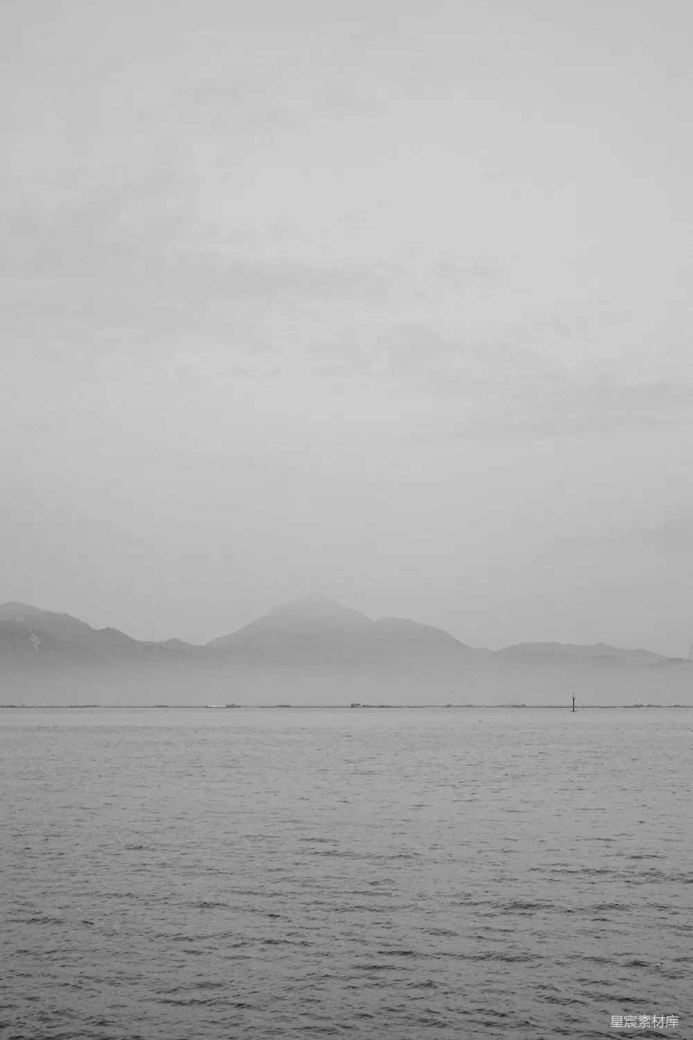 高清摄影 雾蒙蒙的山峦耸立在一片宁静的海面上。