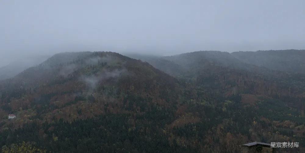 高清摄影 山间雾气缭绕，前景有一座小屋。