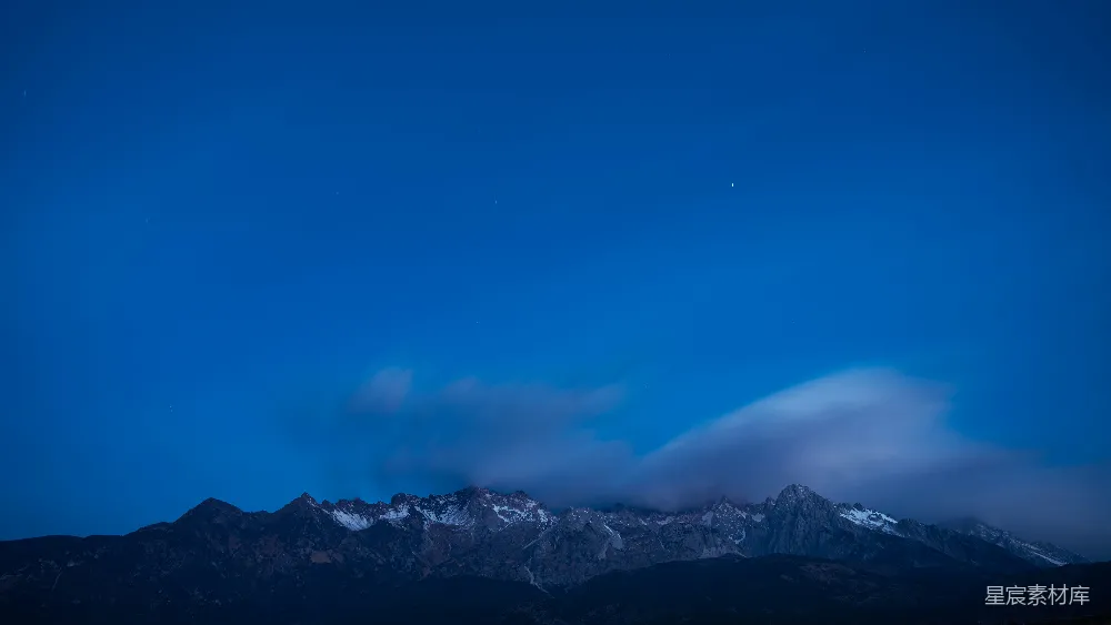 高清摄影 夜空中有云和山峦在背景中。