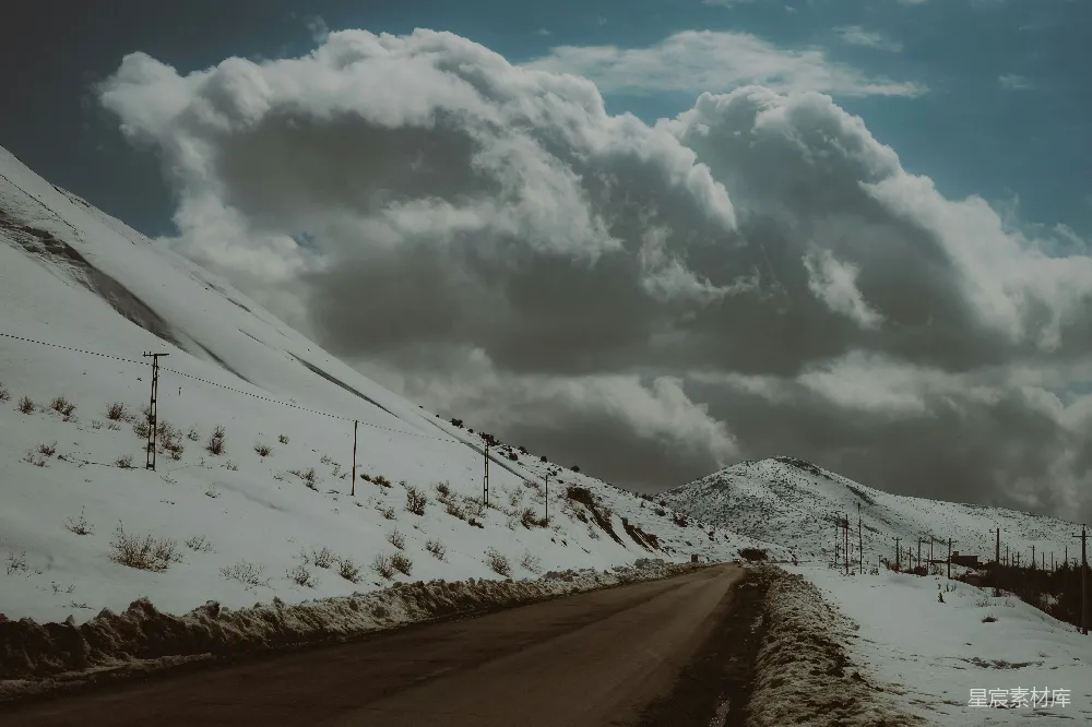 高清摄影 背景中有山的一条被雪覆盖的道路