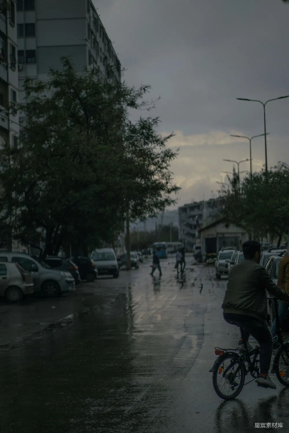 高清摄影 一个男子在一条被雨水浸湿的街道上骑自行车。