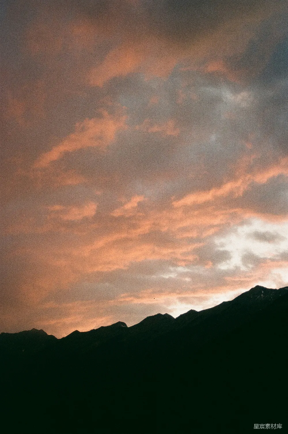 高清摄影 夕阳下粉色的云朵飘过暗山的轮廓影子