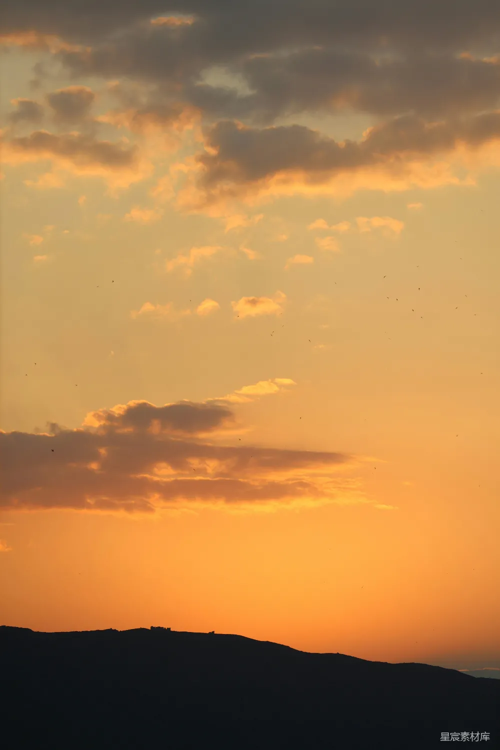 高清摄影 金色夕阳映照在一座被云层遮蔽的山影之上。