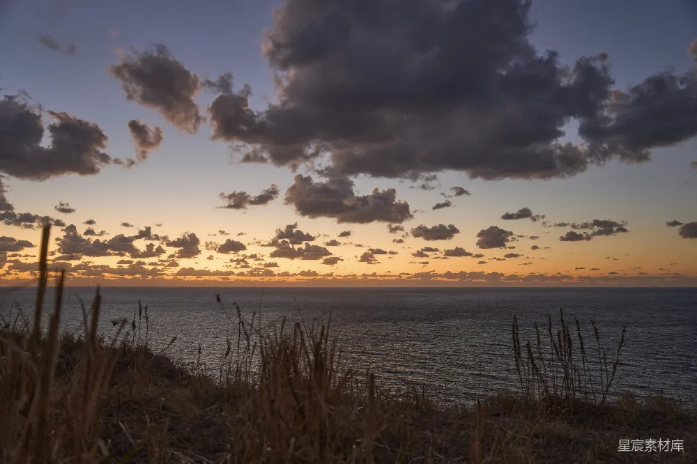 高清摄影 夕阳下的海洋，天空中有云朵。
