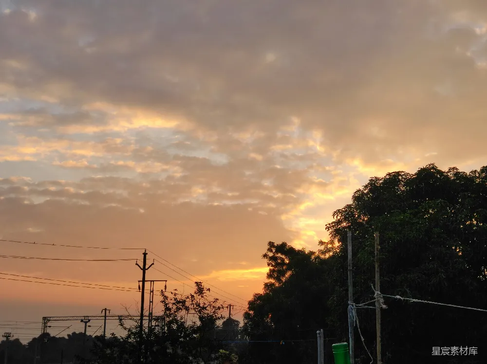高清摄影 夕阳下的天空，云层覆盖着树木和电线杆