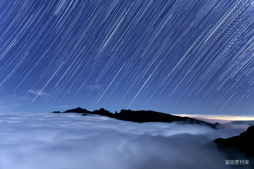 高清摄影 夜空中的星轨横跨云层和山峰之上。