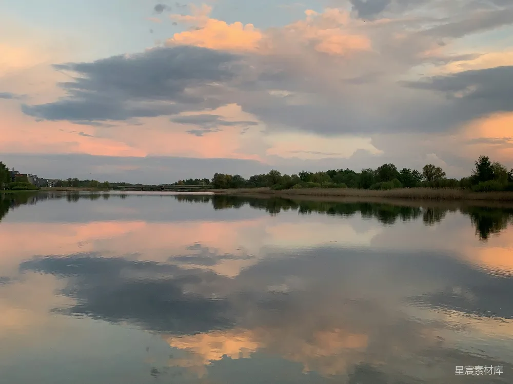 高清摄影 夕阳映照下，柔和的云彩倒映在平静的湖面上。