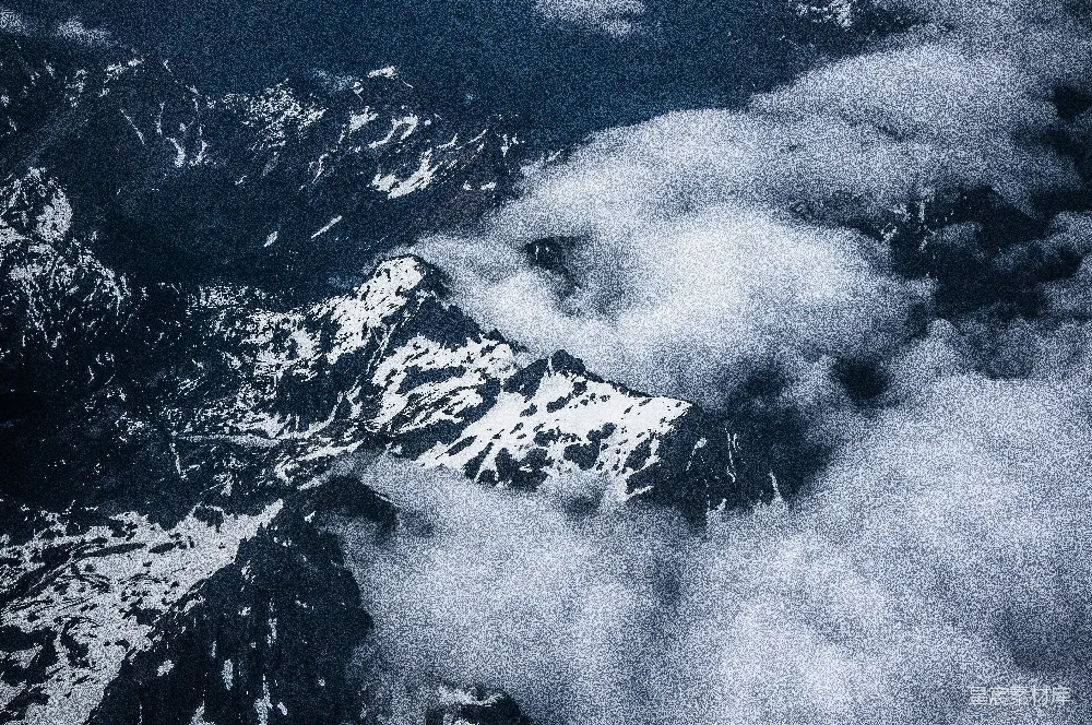 高清摄影 白天的高空照片中，白雪覆盖的灰色山峰上方飘着白云。