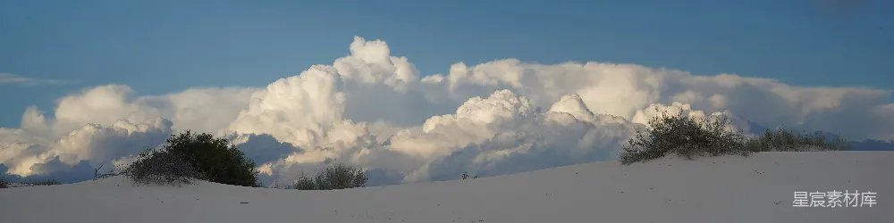 高清摄影 覆盖着白雪的山顶，背景是树木和云朵。