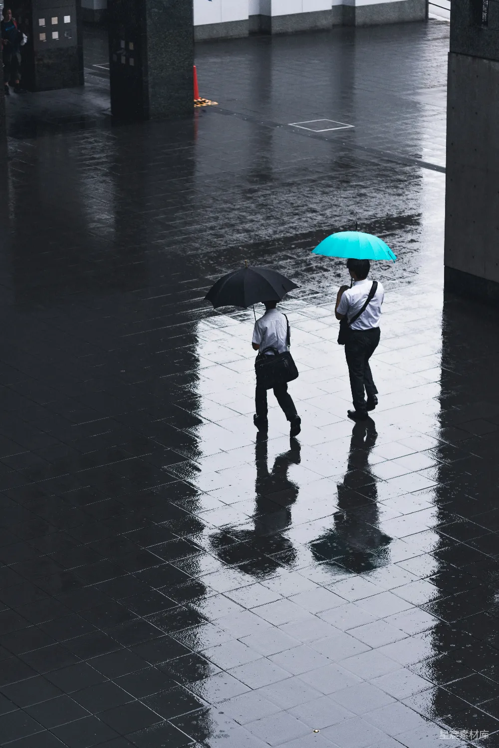 高清摄影 两人在雨中行走于路旁，撑着伞。