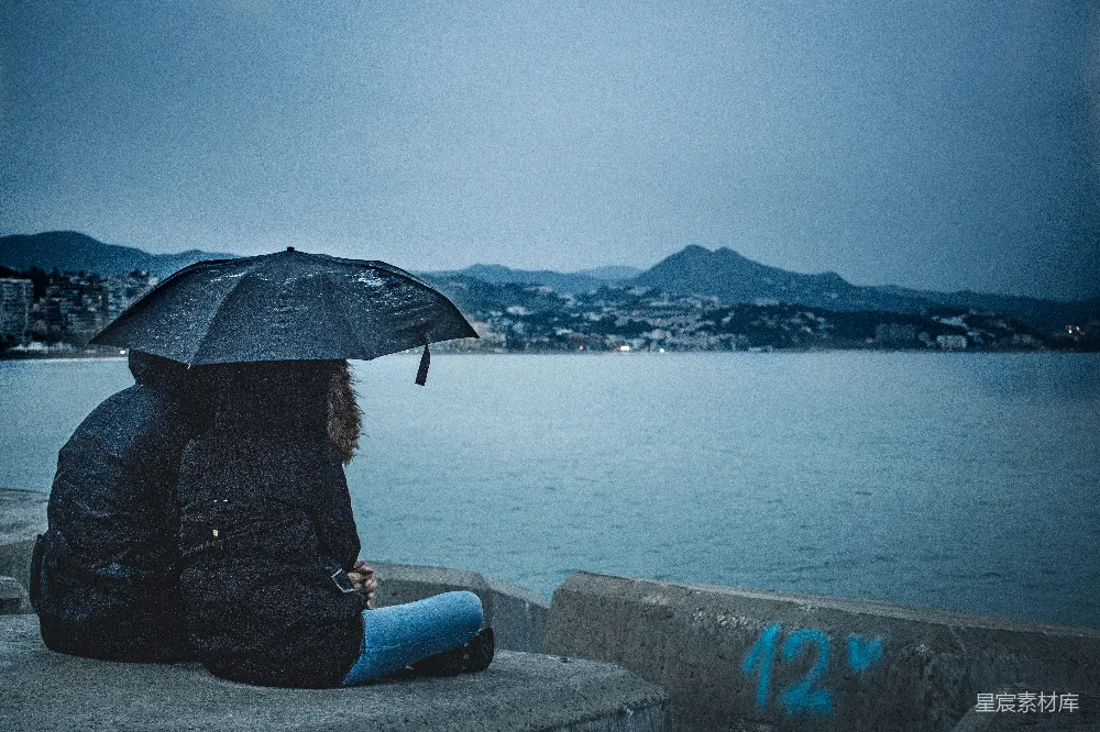 高清摄影 一对手持黑色雨伞的人坐在平静水面的一侧