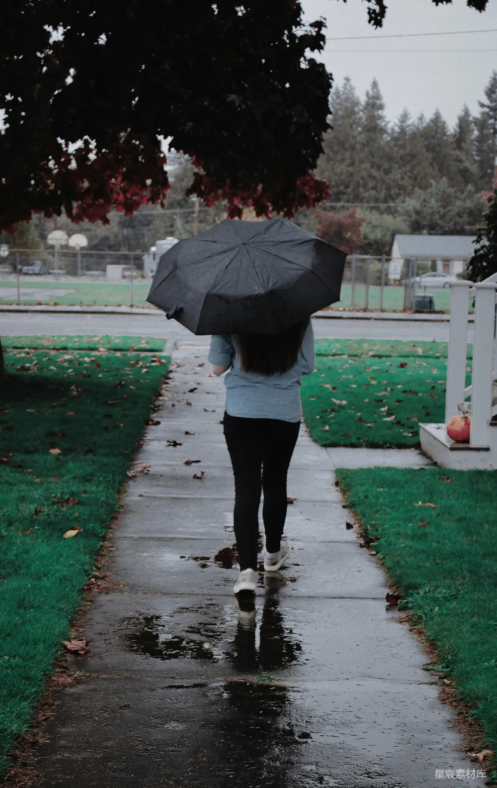 高清摄影 一个女人走在人行道上拿着雨伞